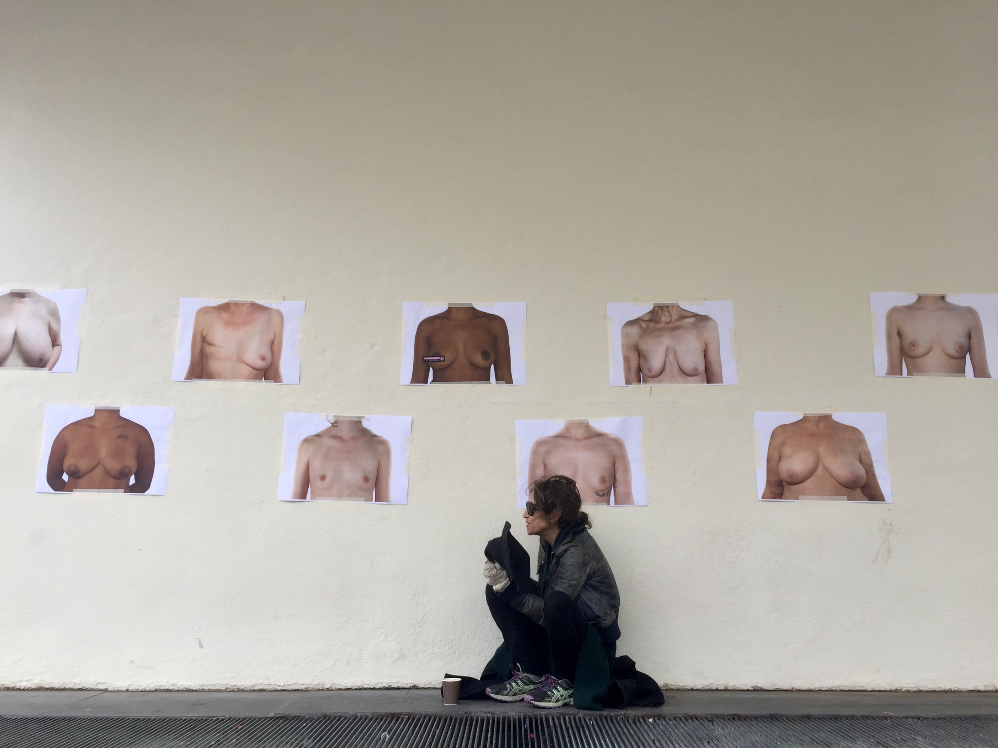 Mujer sin hogar disfrutando de un café frente a una exposición de arte callejero