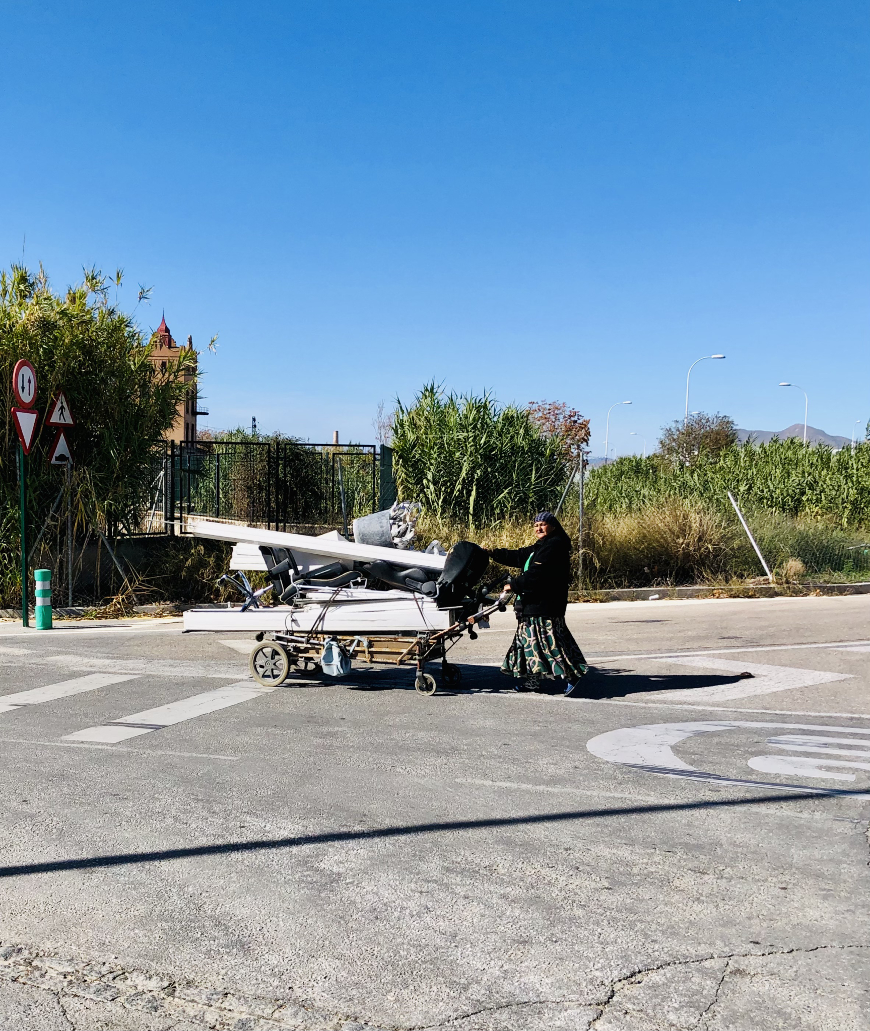 Mujer extranjera llevando un carro con chatarra